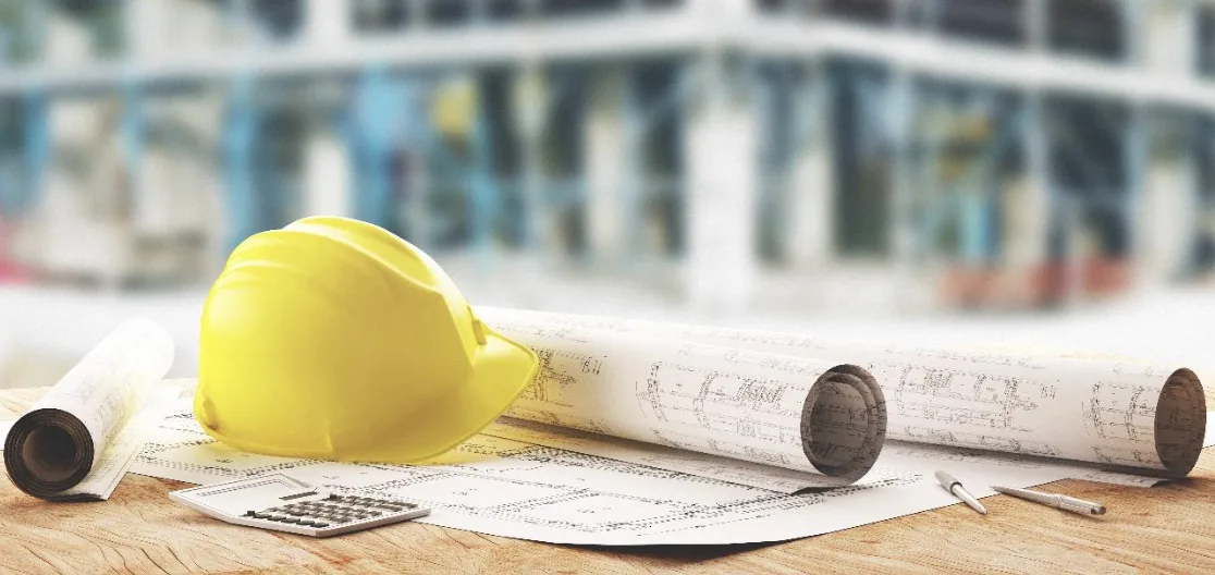 Un casco de obra descansa sobre los planos de construcción