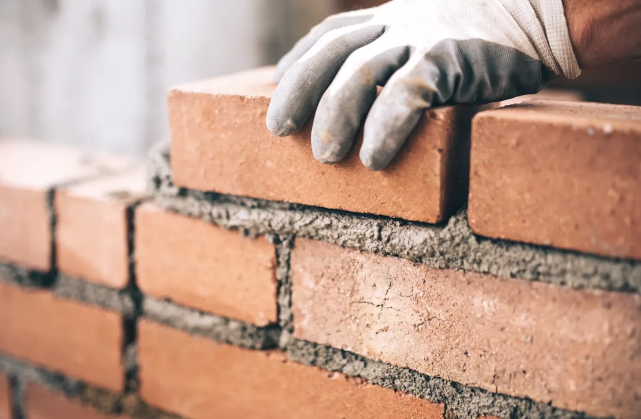 Operaio costruisce un muro di mattoni